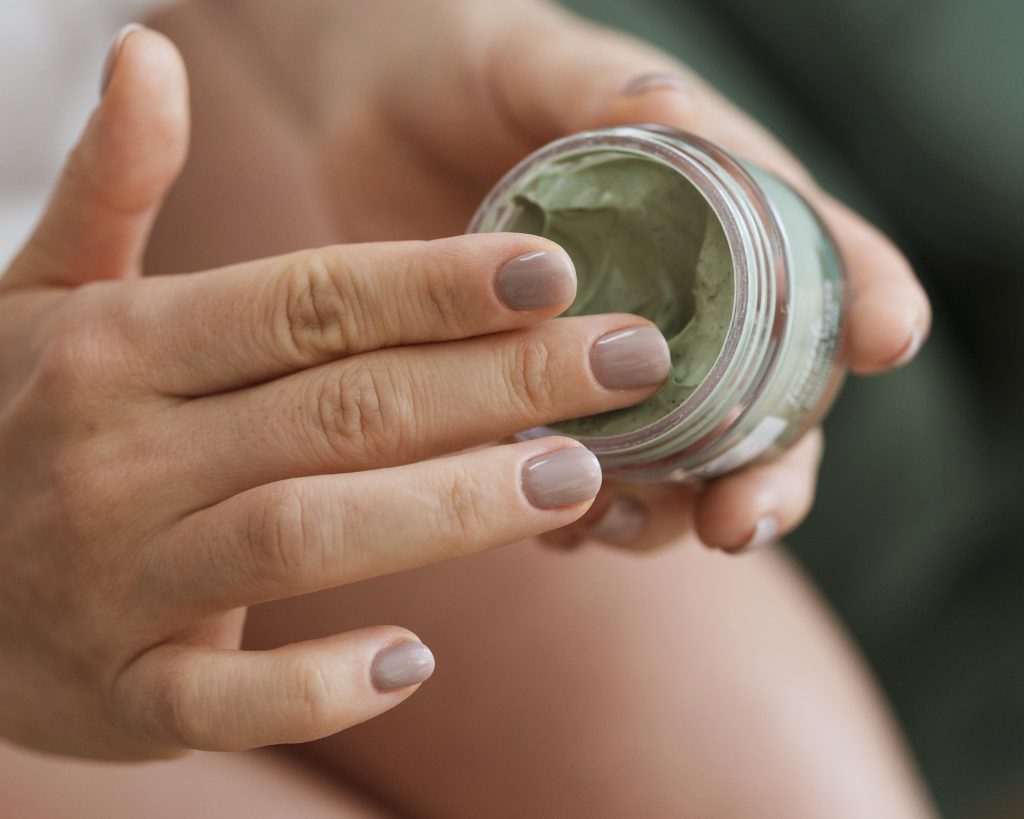 Женщина руками дотрагивается к маски из глины